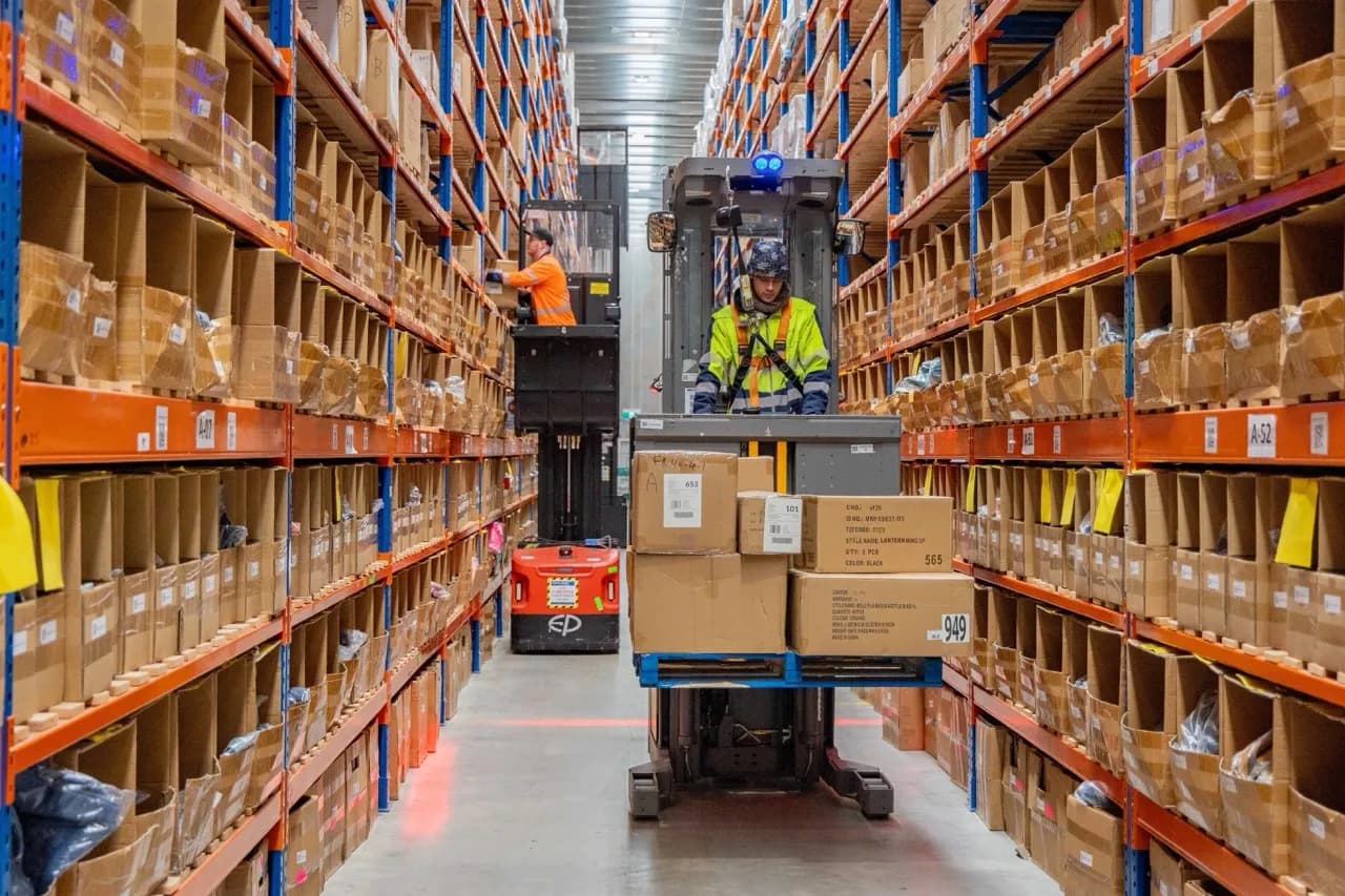 Forklift driver receiving and moving inbound stock through the warehouse aisle