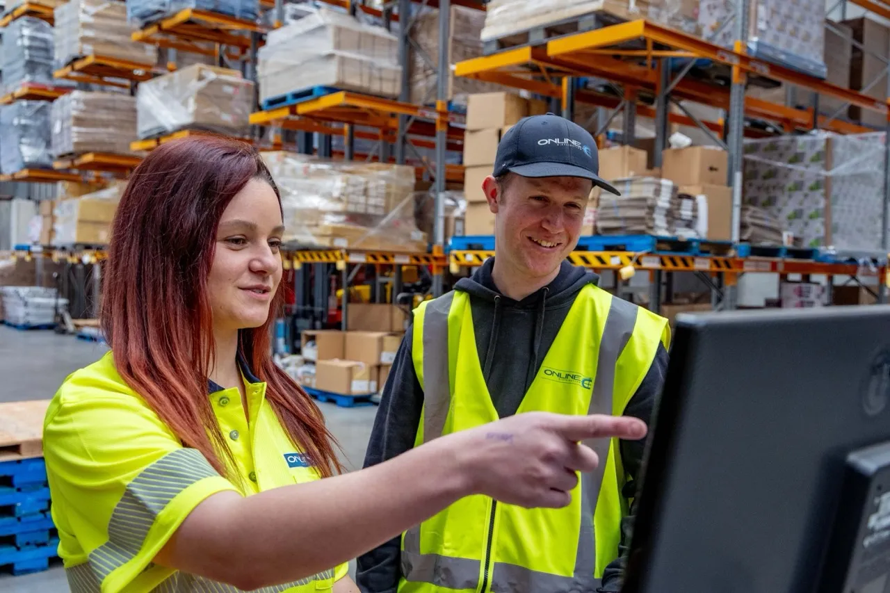 Warehouse staff coordinating returns reporting and service updates from shared workstations